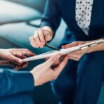 Two business people reviewing a printed contract document with a pen