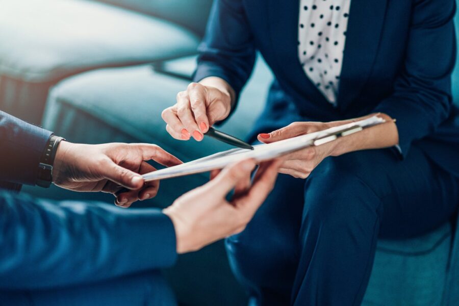 Two business people reviewing a printed contract document with a pen