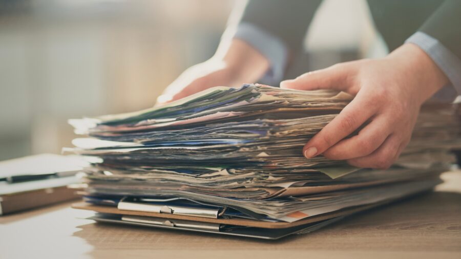 Person reviewing printed agreement documents and files at an office desk